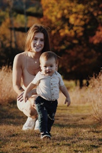 a woman holding a baby in a field