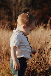 a little boy standing in a field of tall grass