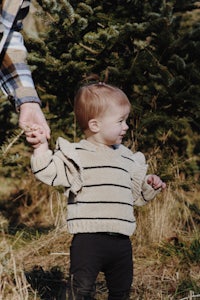 a man holding a little girl's hand in front of a tree