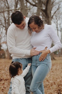 a family is standing in a field with a baby in their arms