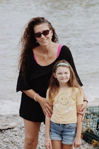 a woman and a little girl standing on the beach