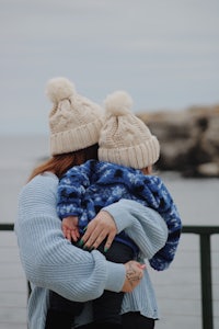 a woman with a baby in her arms holding a hat