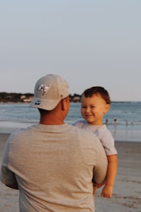 a man holding a child on the beach