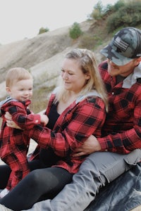 a family sitting on a blanket with a baby in a red flannel shirt