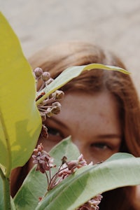 a woman peeking out of a plant