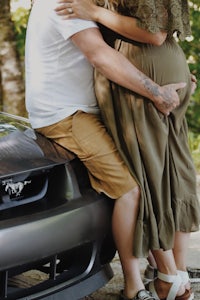 a man and woman hugging on the side of a car