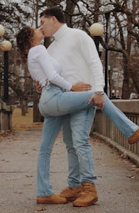 a man and woman kissing on a bridge