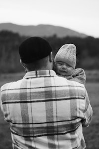 a black and white photo of a man holding a baby in his arms