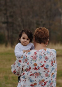 a woman holding a small child in a field