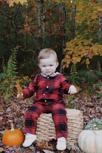 a baby sitting in a basket with pumpkins in the background