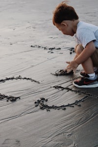 a young boy playing on the beach with a heart drawn in the sand