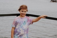 a young girl wearing a tie dye t - shirt