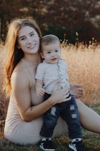 a woman holding a baby in a field