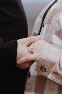 a couple holding each other's hands in front of a mountain