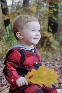 a young boy sitting in a basket holding a leaf