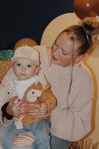 a woman holding a baby in front of balloons