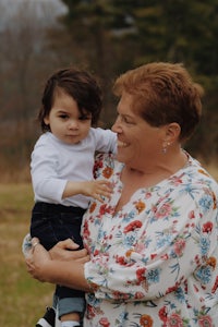 an older woman holding a small child in a field