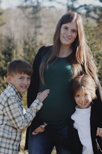 a pregnant woman posing with her children in front of a christmas tree