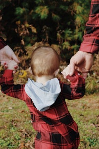 a man holding a baby's hand in the grass