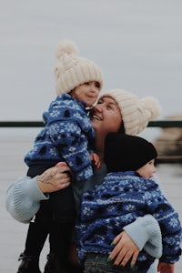 a woman holding her two children on a pier