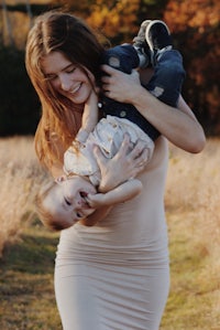 a woman holding a baby in her arms in a field