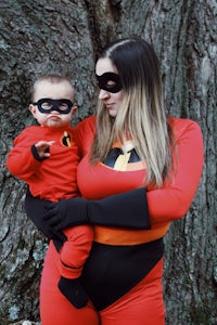 a woman dressed as the incredibles holding a baby