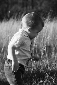 a black and white photo of a toddler in a field