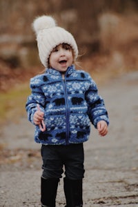 a little girl wearing a blue jacket and boots