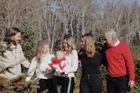 a family is holding a baby in front of a christmas tree