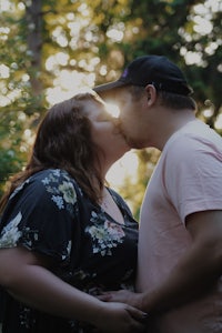 a couple kissing in the woods at sunset