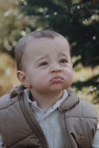 a baby is standing in front of a tree