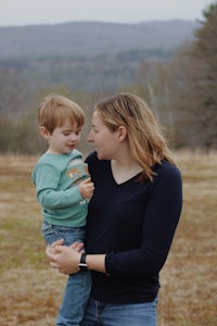 a woman holding a young boy in a field