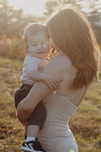 a woman holding a baby in a field