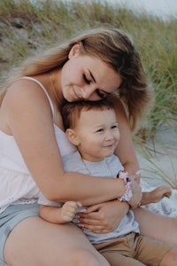 a woman is hugging her son on the beach