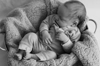 a black and white photo of a baby sleeping in a basket