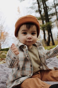 a baby is sitting on a blanket in the woods