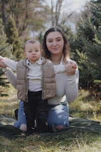 a woman and a child posing in front of a christmas tree farm