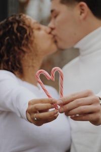 a couple kissing while holding a candy cane