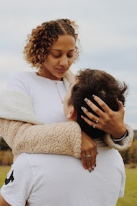 a woman is hugging a man in a field