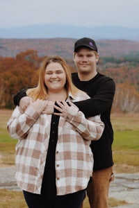 a man and woman posing for a photo in front of a mountain