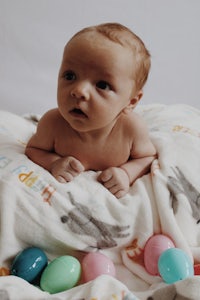 a baby laying on a blanket with colorful easter eggs