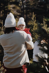 a man holding a baby while walking through a christmas tree farm