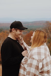 a couple standing on top of a hill with mountains in the background