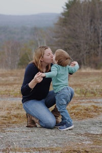 a woman kissing a child on the ground