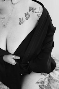 a black and white photo of a woman with tattoos on her chest