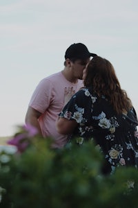 a couple kissing in front of a lake