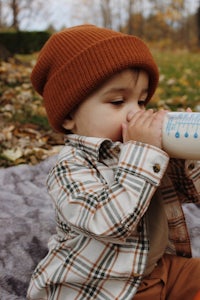 a baby drinking from a bottle in the fall