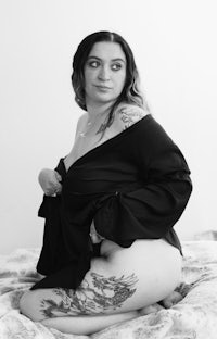 a black and white photo of a woman posing on a bed