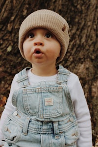 a baby wearing overalls and a beanie