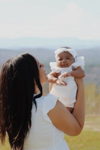 a woman holding her baby in front of a mountain